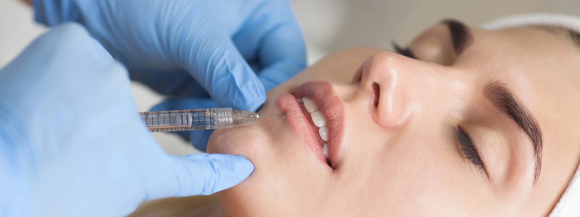 A beautiful woman is receiving lip filler treatment.